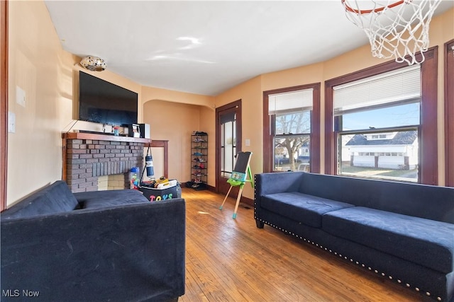 living area featuring light wood finished floors, a fireplace, and baseboards