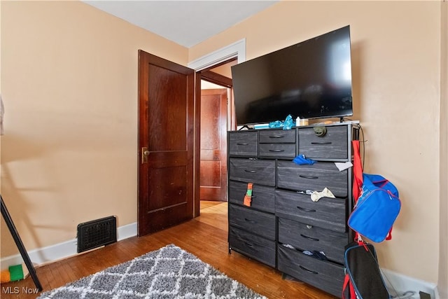 bedroom with visible vents, baseboards, and wood finished floors