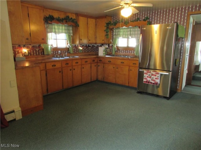 kitchen with a sink, freestanding refrigerator, brown cabinetry, baseboard heating, and ceiling fan