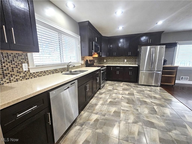 kitchen with visible vents, a sink, stainless steel appliances, light countertops, and decorative backsplash