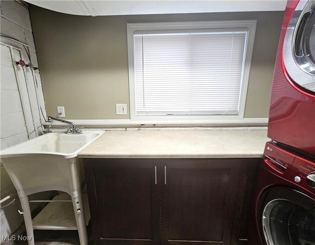 laundry area featuring stacked washer / drying machine and cabinet space