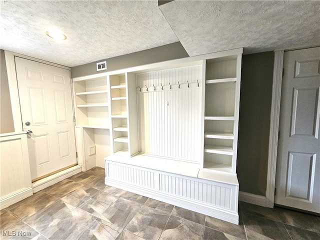 mudroom featuring built in features, visible vents, and a textured ceiling