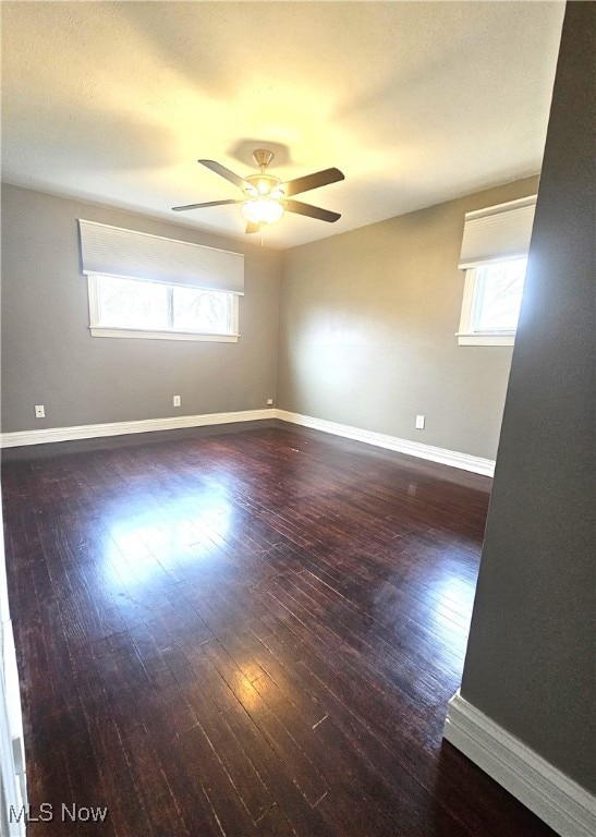 empty room with a ceiling fan, wood finished floors, and baseboards