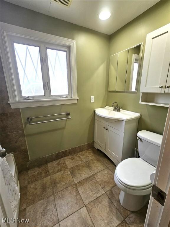 half bathroom featuring vanity, baseboards, radiator heating unit, recessed lighting, and toilet