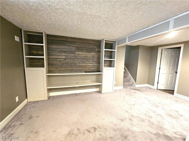 interior space with carpet flooring, a textured ceiling, stairs, and baseboards