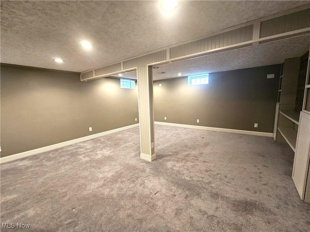 below grade area featuring carpet flooring, a textured ceiling, and baseboards