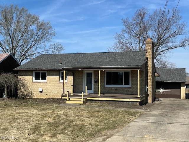 ranch-style home with brick siding, a porch, roof with shingles, a chimney, and driveway