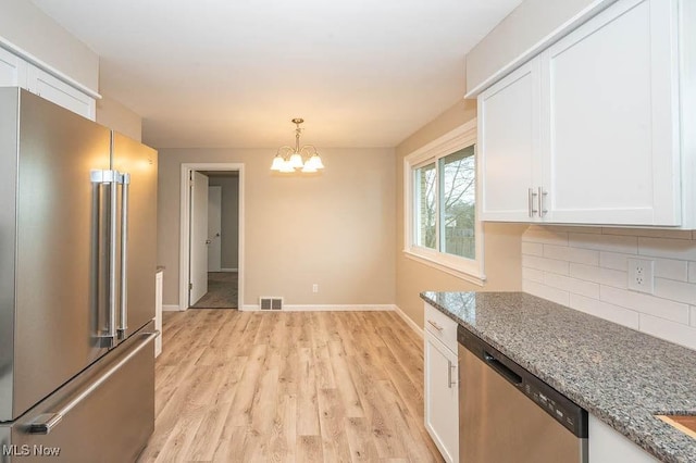 kitchen featuring visible vents, tasteful backsplash, white cabinetry, appliances with stainless steel finishes, and a chandelier