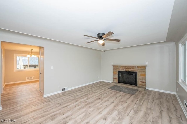 unfurnished living room with visible vents, ceiling fan with notable chandelier, baseboards, and wood finished floors