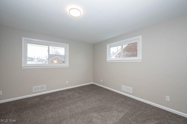 carpeted spare room with a healthy amount of sunlight, visible vents, and baseboards