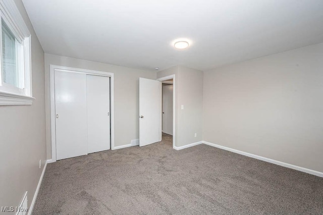 unfurnished bedroom featuring a closet, baseboards, and carpet floors