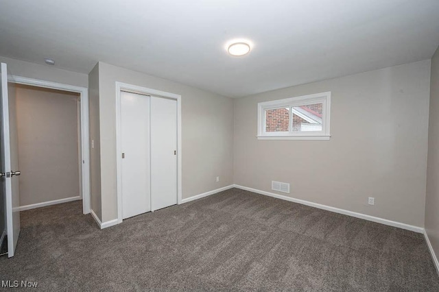 unfurnished bedroom featuring a closet, visible vents, baseboards, and dark colored carpet