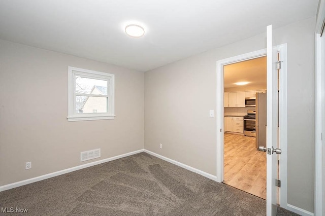 empty room featuring visible vents, baseboards, and light carpet