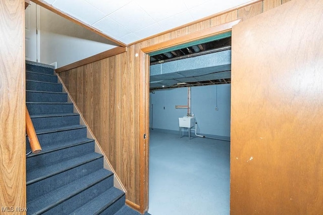 staircase with wooden walls and finished concrete flooring