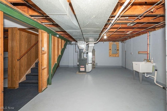 below grade area featuring heating unit, stairway, electric panel, and a sink