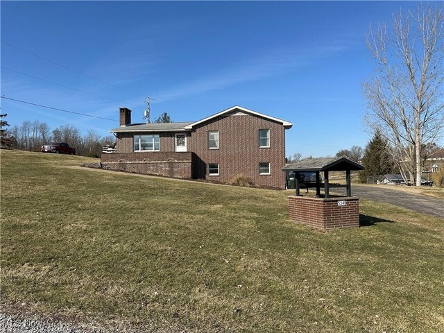 rear view of property featuring a yard, brick siding, and a chimney