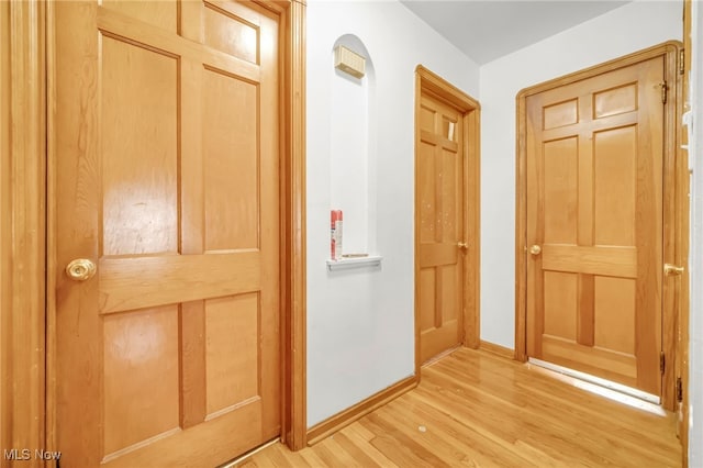 corridor featuring baseboards and light wood-style floors