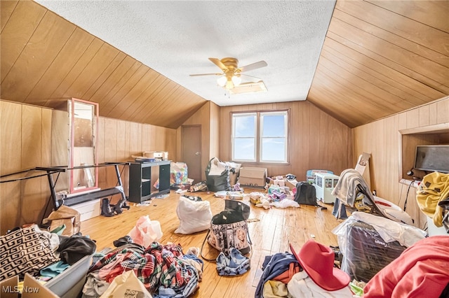 bonus room with wooden walls, a textured ceiling, lofted ceiling, and hardwood / wood-style flooring