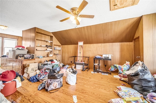 additional living space featuring ceiling fan, wood walls, lofted ceiling, wood finished floors, and a textured ceiling