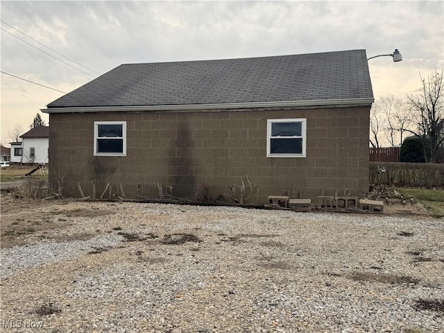 view of side of home with concrete block siding and a shingled roof