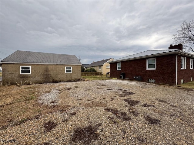 view of side of property featuring brick siding, a chimney, and metal roof