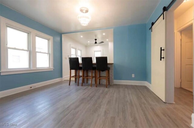 dining space featuring a barn door, baseboards, and wood finished floors