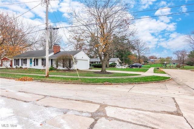 view of front of house featuring a front yard, an attached garage, driveway, and a chimney