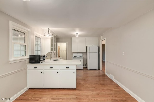 kitchen with white cabinetry, white appliances, a peninsula, and a sink