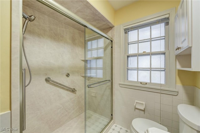 bathroom with a stall shower, toilet, and tile walls