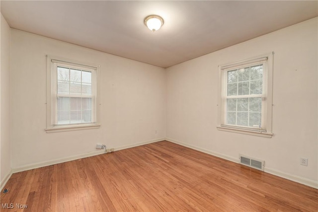 spare room with visible vents, baseboards, and wood finished floors