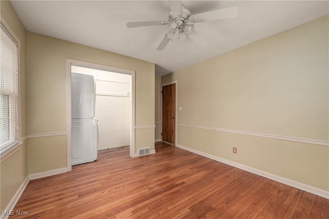 unfurnished bedroom featuring visible vents, light wood-style flooring, freestanding refrigerator, baseboards, and ceiling fan