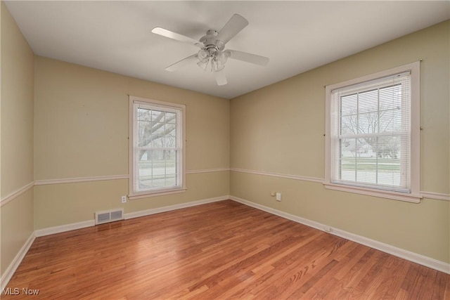 empty room with a healthy amount of sunlight, visible vents, and light wood finished floors