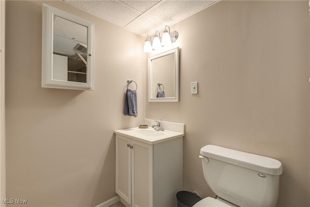 bathroom with vanity, toilet, and a drop ceiling