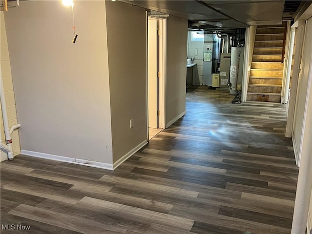 corridor featuring stairway, gas water heater, dark wood-type flooring, and baseboards