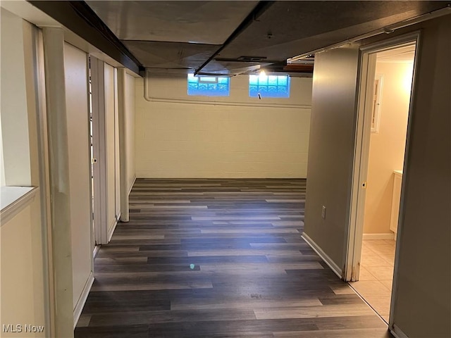 basement with concrete block wall, baseboards, and wood finished floors