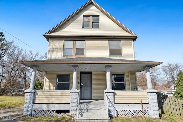 american foursquare style home with a porch and fence