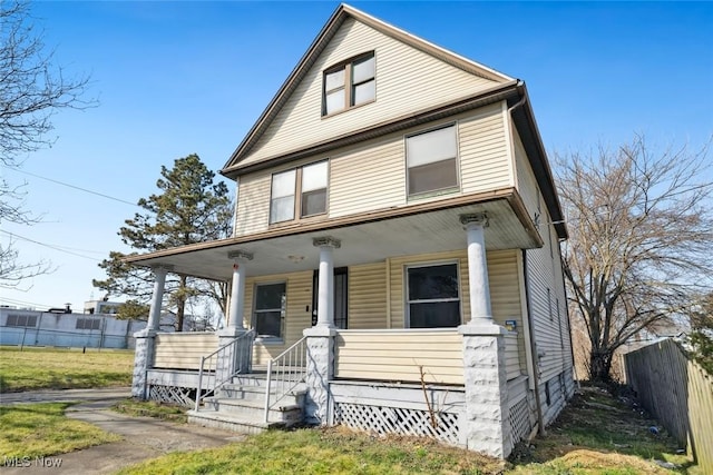 american foursquare style home featuring a porch and fence