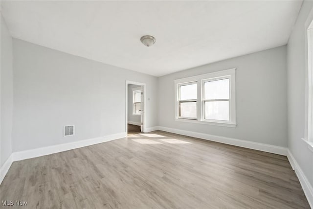 empty room featuring wood finished floors, visible vents, and baseboards