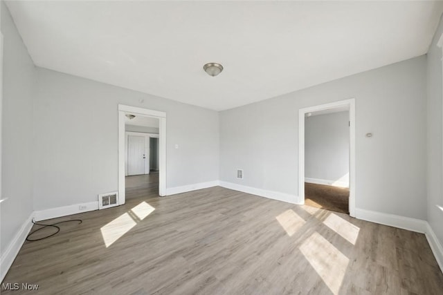 empty room with visible vents, baseboards, and wood finished floors