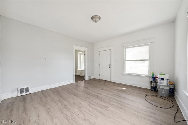 unfurnished room with wood finished floors, visible vents, and baseboards