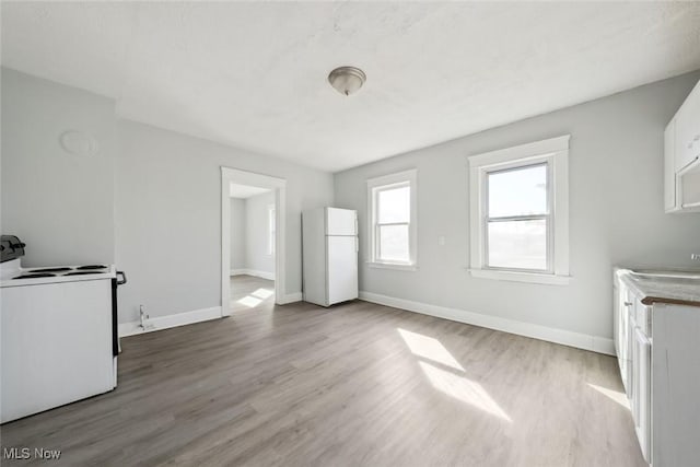 unfurnished living room featuring baseboards and wood finished floors