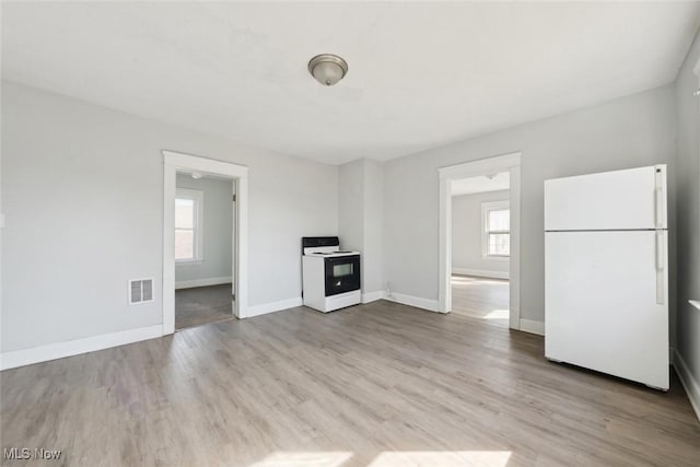 unfurnished living room featuring visible vents, baseboards, and wood finished floors