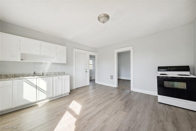 kitchen featuring white cabinets, light wood-style flooring, electric range oven, and a sink