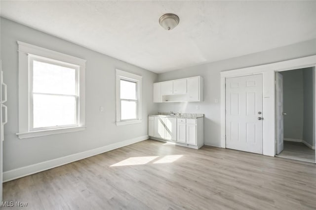 interior space featuring light wood-type flooring, baseboards, and a sink