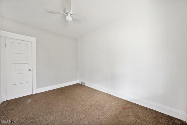 carpeted spare room featuring baseboards and a ceiling fan