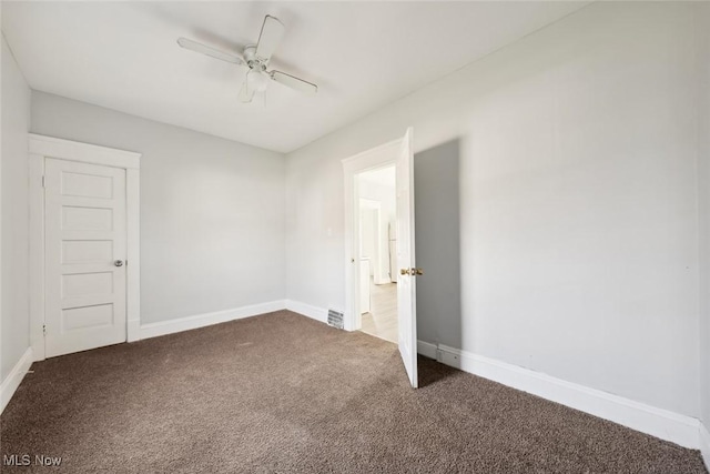 unfurnished room with a ceiling fan, baseboards, and dark carpet