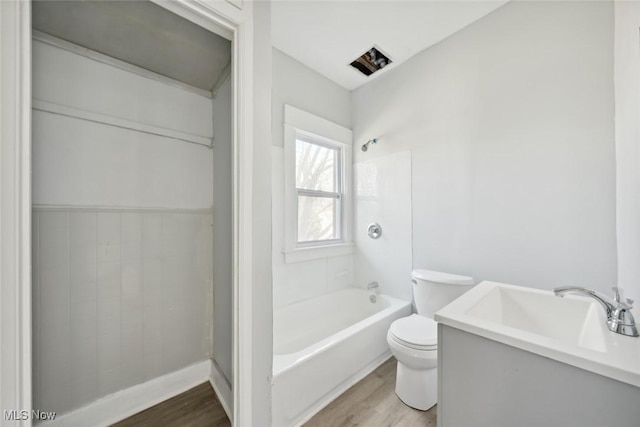 bathroom featuring toilet, shower / washtub combination, wood finished floors, and vanity