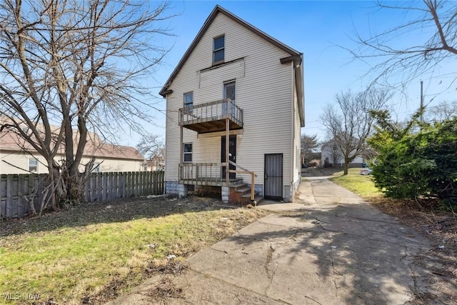 back of property featuring a balcony and fence