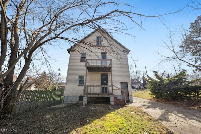 view of front of house featuring a balcony and fence