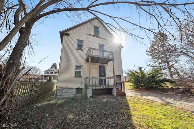 rear view of house with a balcony and fence